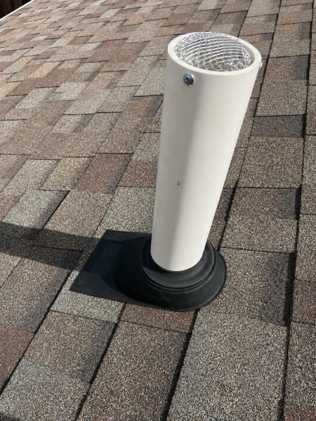 Radon vent terminating above the roofline with a flashed boot and mesh cap