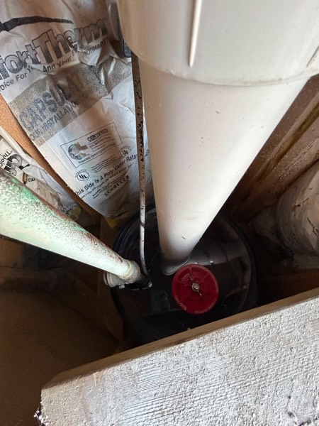 Inside a sealed sump pit: the radon pipe and pump discharge passing through the airtight lid