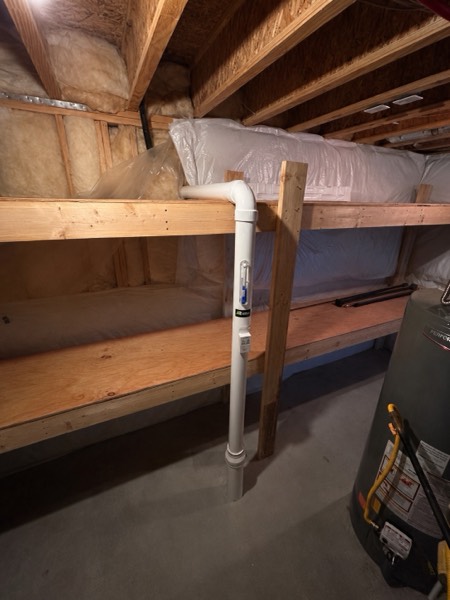 Radon suction point rising through the floor joists of an insulated crawl space