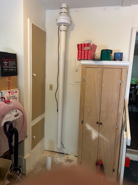 Interior radon pipe and fan installed in a utility room corner