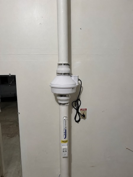 Interior radon fan and pipe mounted cleanly on a basement wall