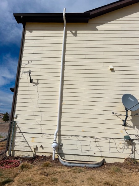 Full-height exterior radon vent on a cream lap-sided home